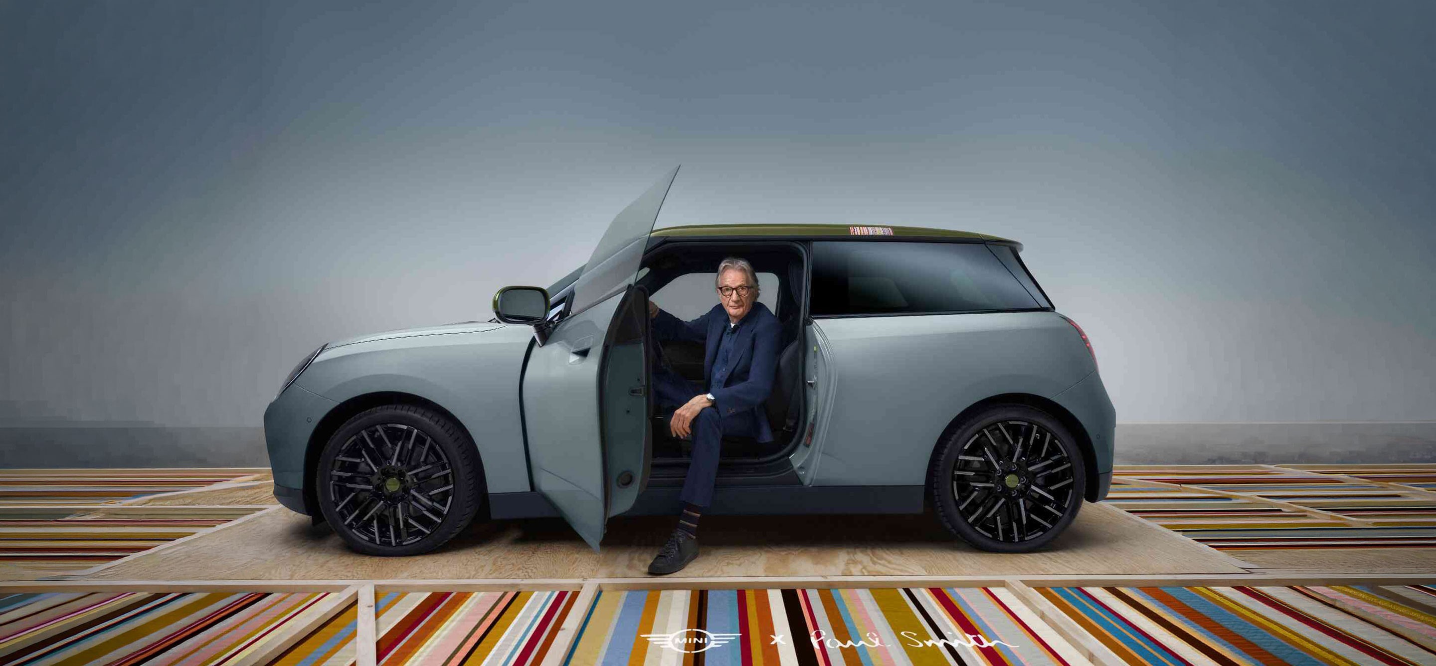 Front side view of the all-electric MINI Cooper Paul Smith Edition in Inspired White with designer Paul Smith